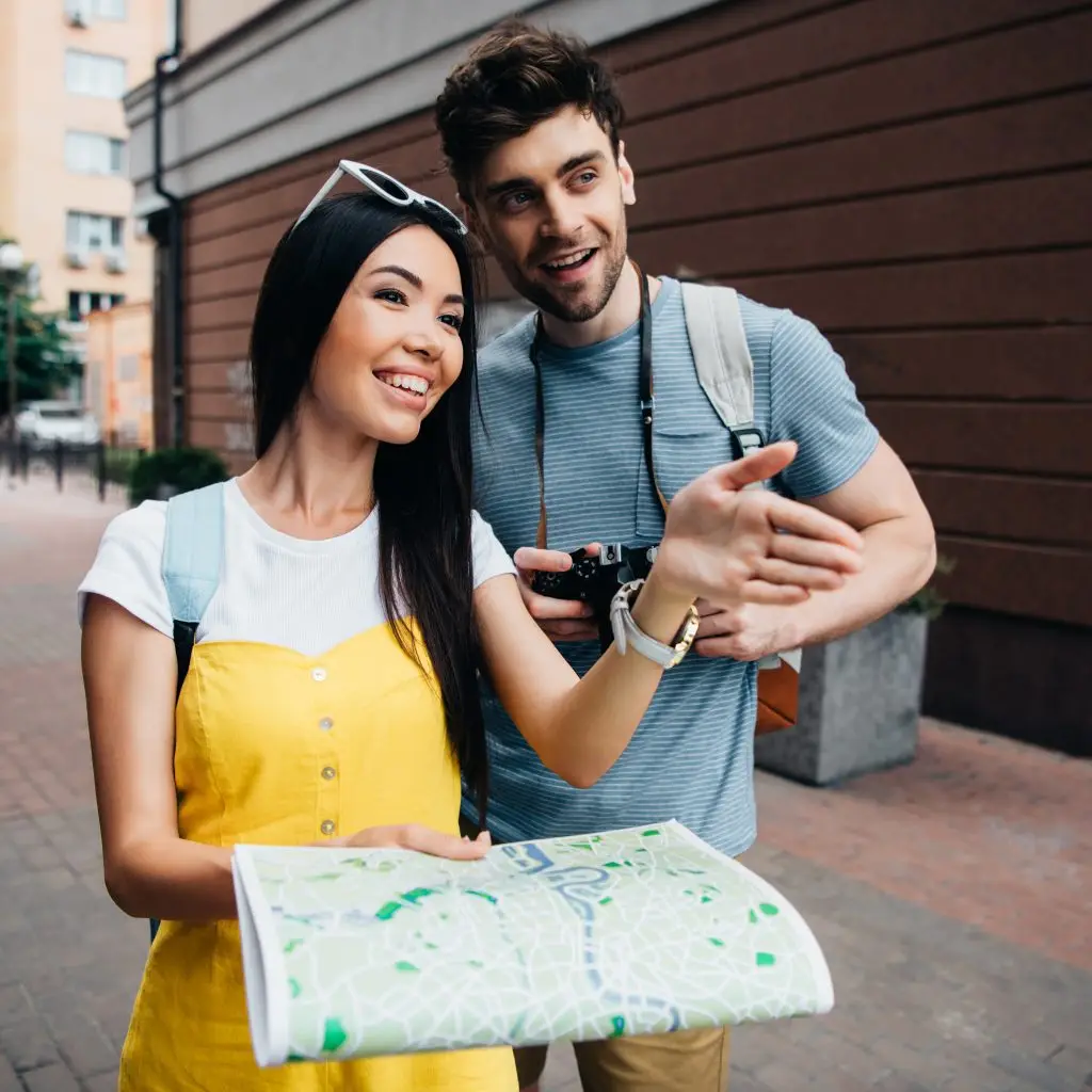 handsome man looking away and asian woman holding map
