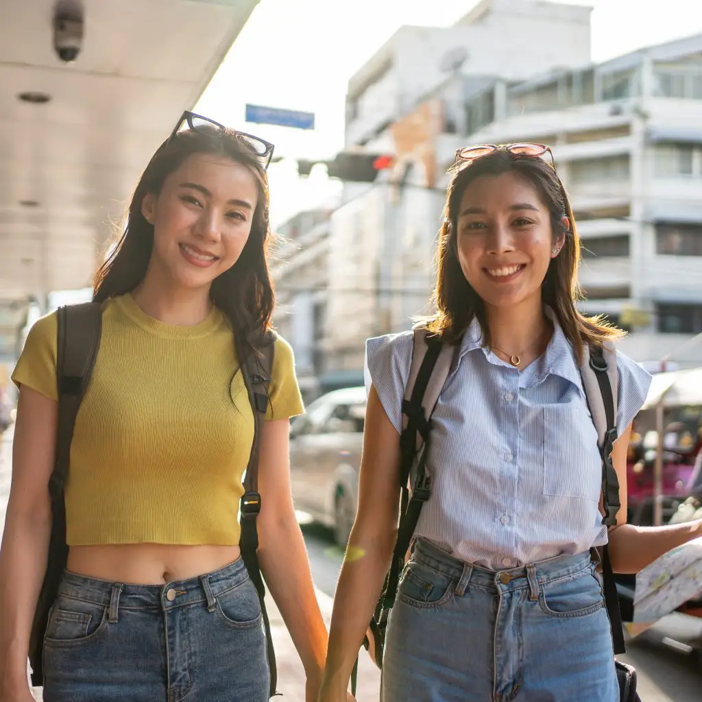 Portrait of Asian women backpacker friend traveling outdoor in the city. Attractive girls tourist feeling happy and relax, walking on street enjoy spend free leisure time for holiday vacation together